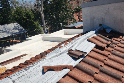 Workers aligning standing seam metal panels on a Lenoir City house roof